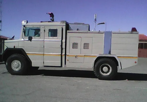 Side view of a pale armoured water cannon truck with a roof-mounted cannon